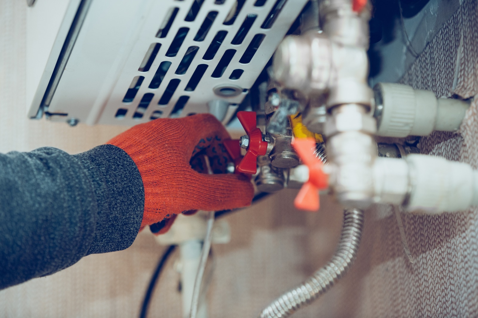 A gloved hand on a red valve